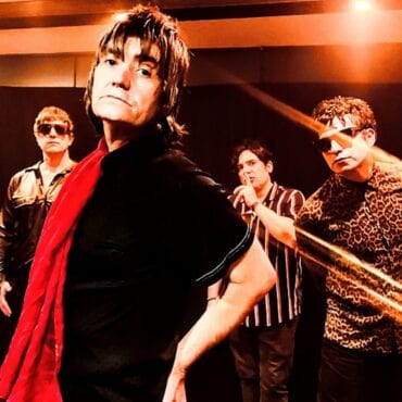 Juana la Loca y banda en escenario con luces y estilo rock.