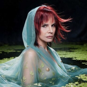Fabiana Cantilo con cabello rojo y vestido transparente en un lago con nenúfares.